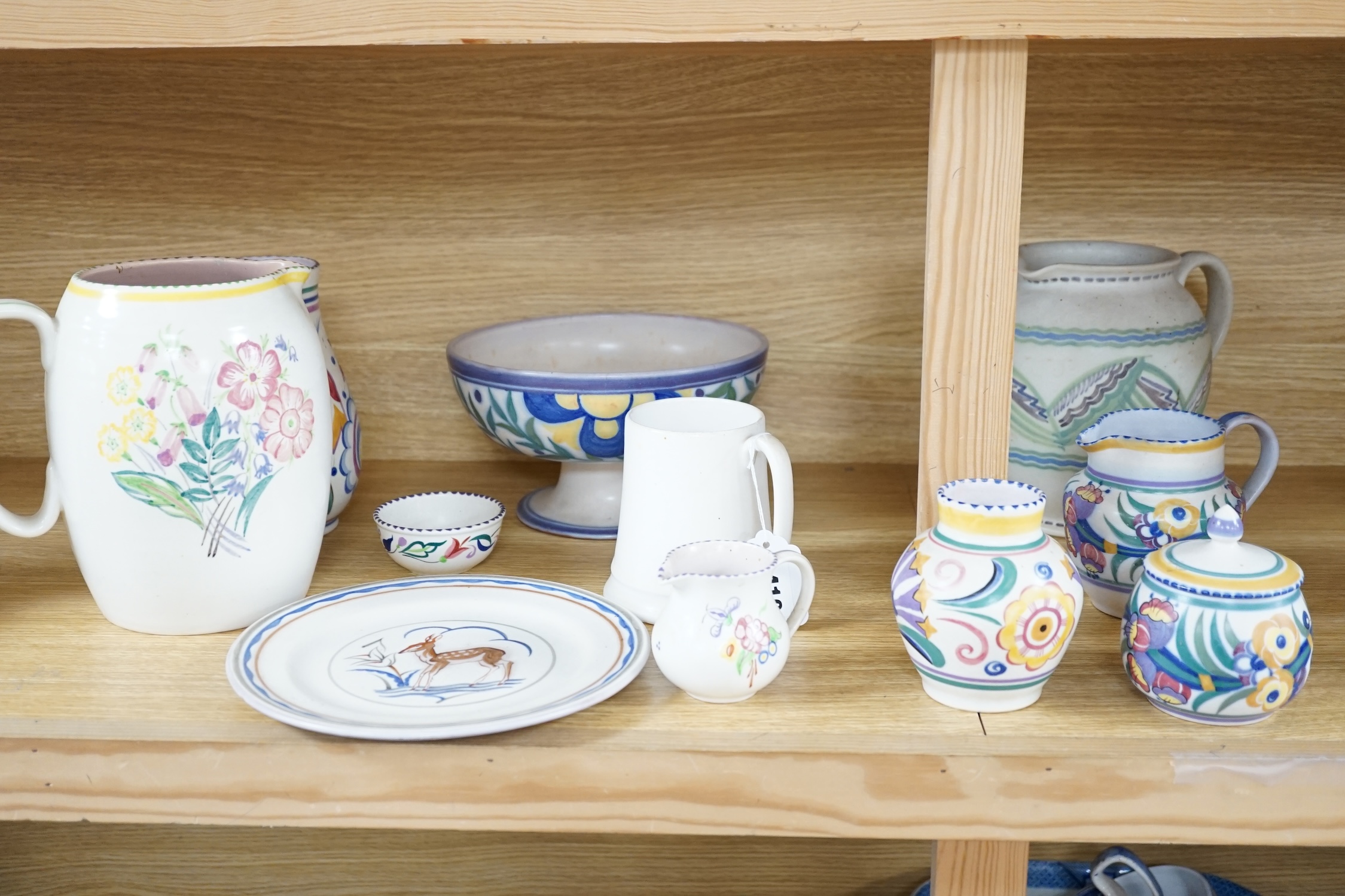 Eleven items of Poole pottery, from 1930’s to 50’s, including vases, jugs, mug and pedestal dish and pot and cover, tallest 19.5cm high. Condition - fair to good